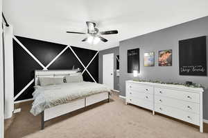 Bedroom with light colored carpet, ceiling fan, and an accent wall