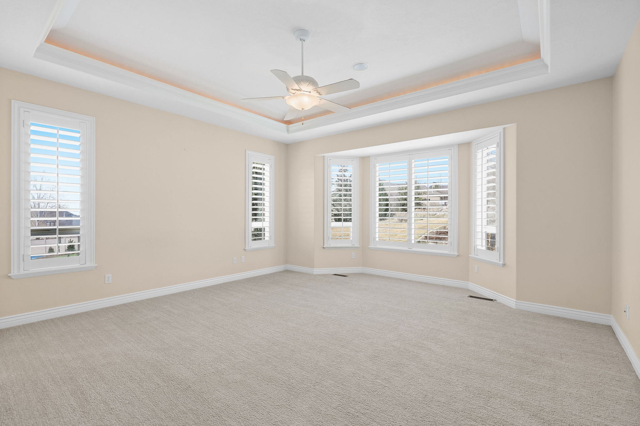 Unfurnished room featuring light carpet, a ceiling fan, plenty of natural light, and a raised ceiling