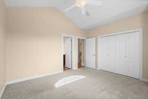 Unfurnished bedroom featuring carpet floors, a closet, lofted ceiling, ceiling fan, and connected bathroom