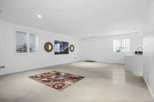 Unfurnished living room featuring finished concrete flooring and recessed lighting