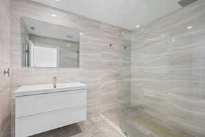 Full bathroom featuring tile walls, a walk in shower, and vanity