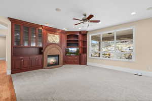 Unfurnished living room with ceiling fan, a brick fireplace, recessed lighting, and built in features