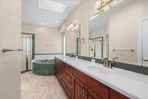 Bathroom featuring double vanity, a stall shower, a skylight, a bath, and recessed lighting
