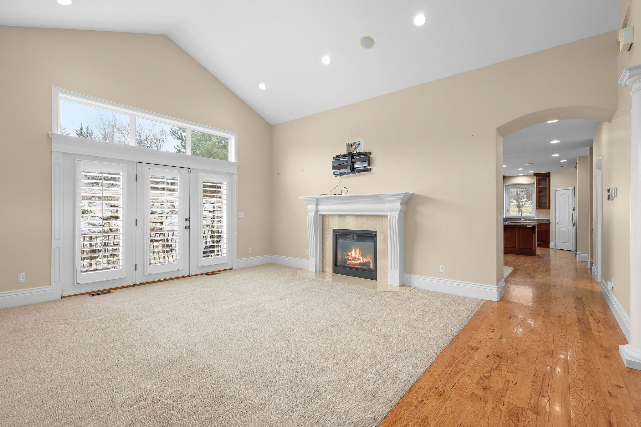 Unfurnished living room with healthy amount of natural light, arched walkways, a high end fireplace, recessed lighting, and lofted ceiling