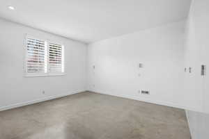 Spare room featuring baseboards and concrete flooring