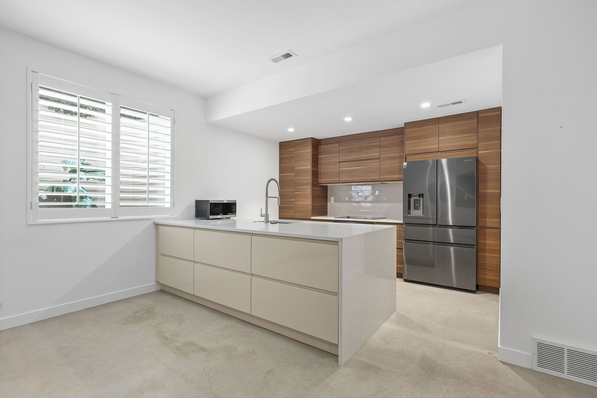 Kitchen with modern cabinets, stainless steel appliances, a peninsula, wood finish cabinetry, and light stone counters
