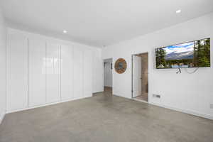 Unfurnished bedroom with concrete floors, ensuite bath, and recessed lighting