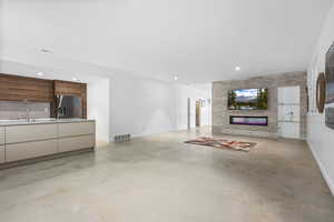 Unfurnished living room with a fireplace, finished concrete floors, and recessed lighting