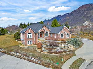 View of front of house featuring brick siding, a front lawn, and a mountain view
