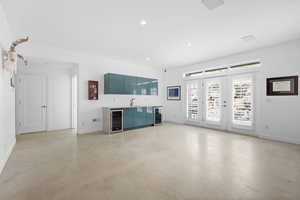 Unfurnished living room featuring bar with sink, concrete floors, wine cooler, and recessed lighting
