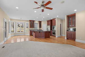Kitchen with glass fronted cabinets, a breakfast bar area, a center island, suspended lighting, and a ceiling fan