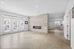 Unfurnished living room with concrete flooring, recessed lighting, and a stone fireplace