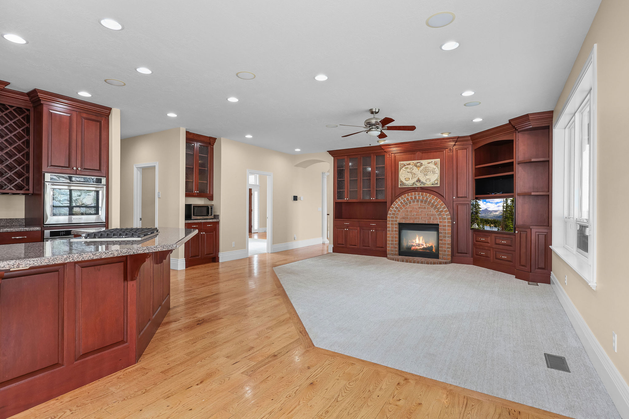 Kitchen featuring arched walkways, a brick fireplace, recessed lighting, light wood-type flooring, and light stone counters