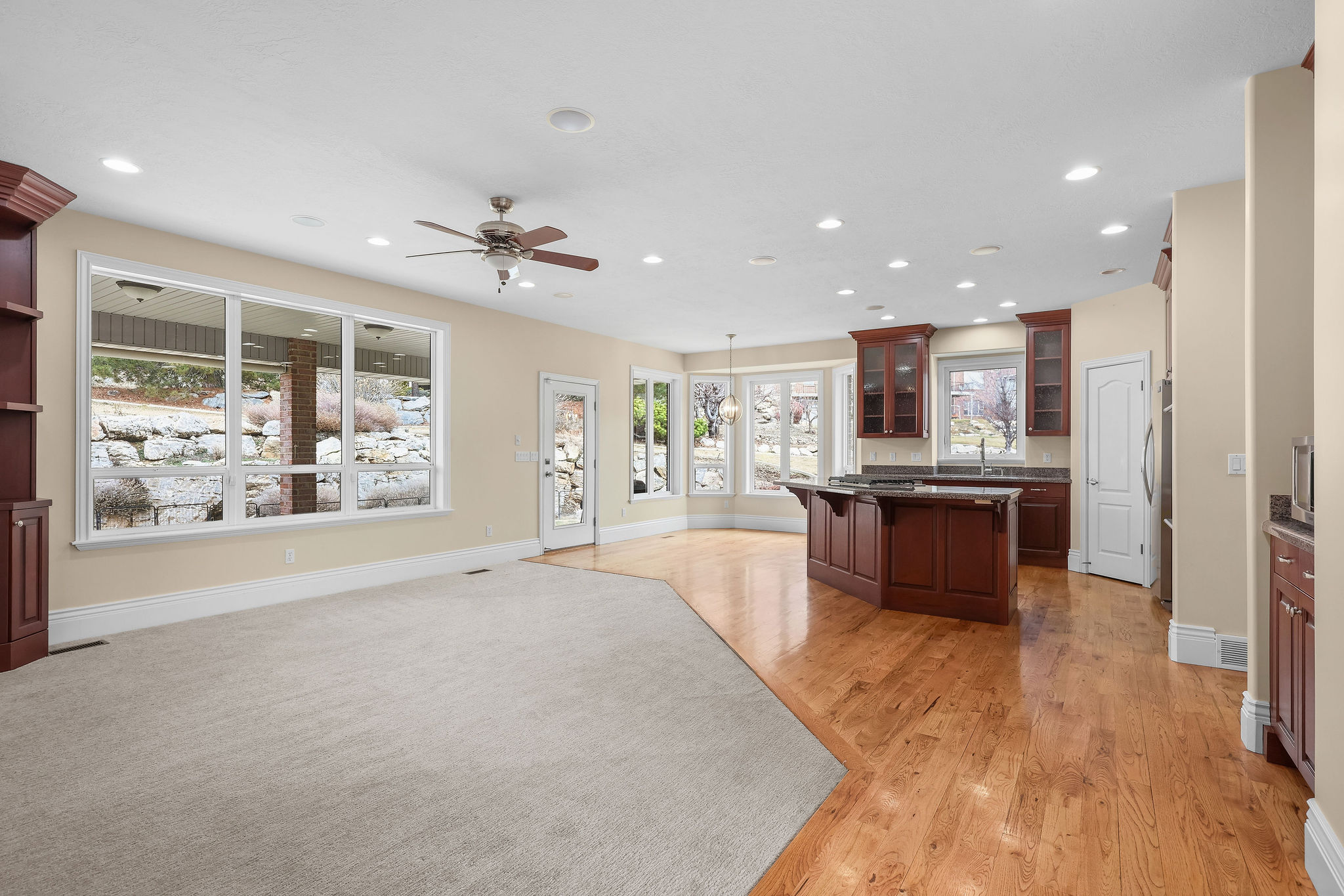 Kitchen with glass fronted cabinets, a kitchen bar, open floor plan, dark stone counters, and ceiling fan