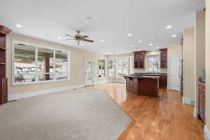 Kitchen with glass fronted cabinets, a kitchen bar, open floor plan, dark stone counters, and ceiling fan