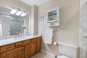 Primary bath featuring a marble finish shower, vanity, and light tile patterned floors