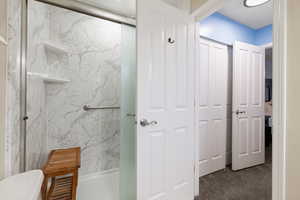 Primary Bathroom with a marble finish shower and dark carpet
