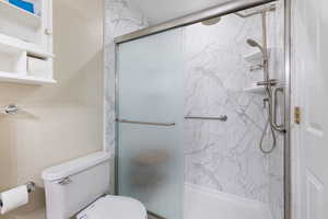 Primary Bathroom with toilet and a marble finish shower