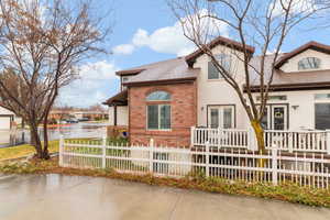 View of front of property featuring brick siding, a fenced front yard, and a shingled roof
