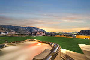 Yard at dusk with a lawn, a mountain view, a jacuzzi, and a patio