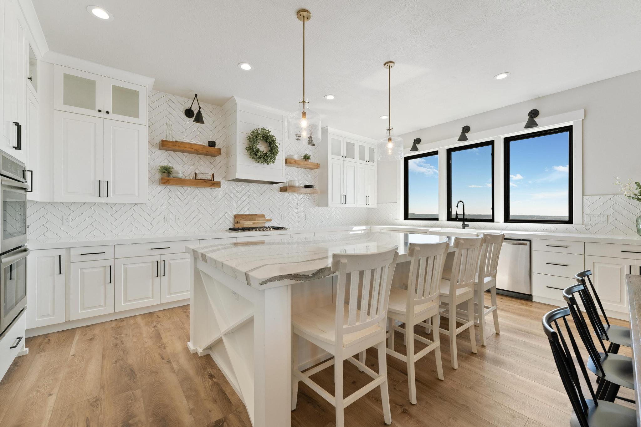 Kitchen with glass insert cabinets, light stone counters, and white cabinets