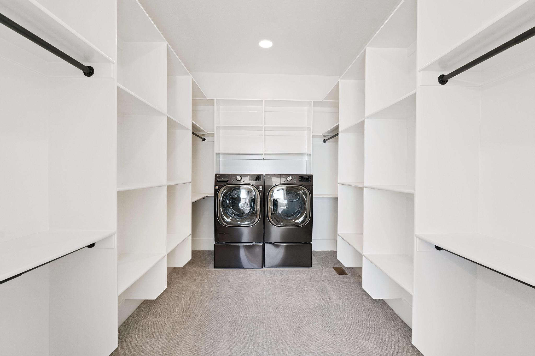 Laundry room featuring light colored carpet and washing machine and clothes dryer