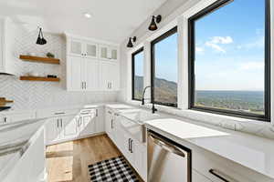 Kitchen featuring white cabinets, stainless steel dishwasher, glass insert cabinets, light wood-style flooring, and recessed lighting