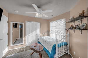 Carpeted bedroom with a ceiling fan, a closet, and a textured ceiling