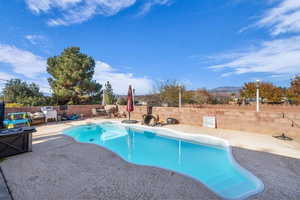 View of swimming pool featuring a fenced backyard, patio surround, and a mountain view