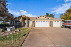 Single story home with stucco siding, stone siding, a garage, and driveway