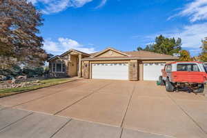 Single story home with stone siding, stucco siding, a garage, and concrete driveway