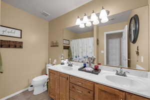 Full bathroom with double vanity, a shower with curtain, and light tile patterned flooring
