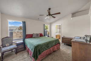 Bedroom with light colored carpet, ceiling fan, vaulted ceiling, and connected bathroom