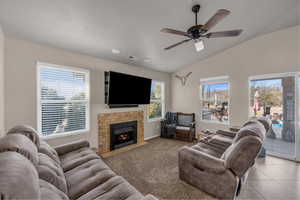 Living room featuring lofted ceiling, ceiling fan, and a fireplace with flush hearth