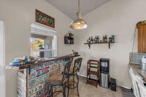Indoor dry bar with light tile patterned floors, pendant lighting, and open shelves