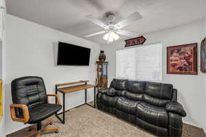 Living room with carpet, a textured ceiling, and ceiling fan