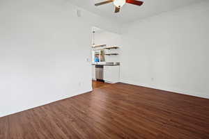Empty room featuring dark wood-type flooring, crown molding, and a ceiling fan