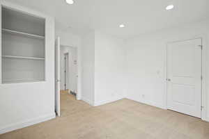 Unfurnished bedroom with light carpet and recessed lighting