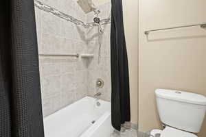 Bathroom with toilet and shower / tub combo with curtain