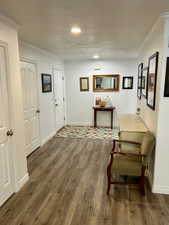 Hall featuring ornamental molding, dark wood finished floors, and a textured ceiling