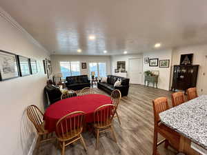 Dining area with wood finished floors, a textured ceiling, and recessed lighting