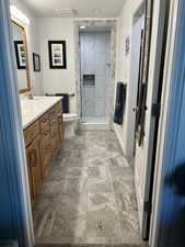 Bathroom featuring double vanity, a shower stall, and stone finish flooring
