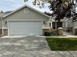 Single story home featuring an attached garage, concrete driveway, and stucco siding