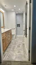 Full bath with vanity, a shower stall, recessed lighting, and light stone finish flooring