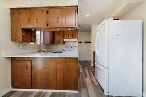 Kitchen with white appliances, light countertops, wood finish cabinetry, a peninsula, and dark wood-type flooring