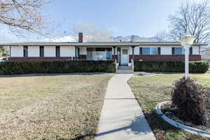 Single story home with a front yard, brick siding, a porch, and a chimney