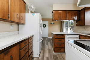 Kitchen with white appliances, light countertops, light wood-type flooring, and wood finish cabinetry