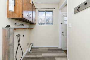 Laundry area featuring hookup for a washing machine, light wood-type flooring, cabinet space, and electric dryer hookup