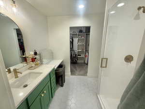 Full bathroom with vanity, a walk in closet, a stall shower, light tile patterned floors, and recessed lighting