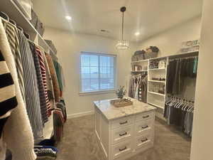 Walk in closet featuring dark carpet and hanging lights